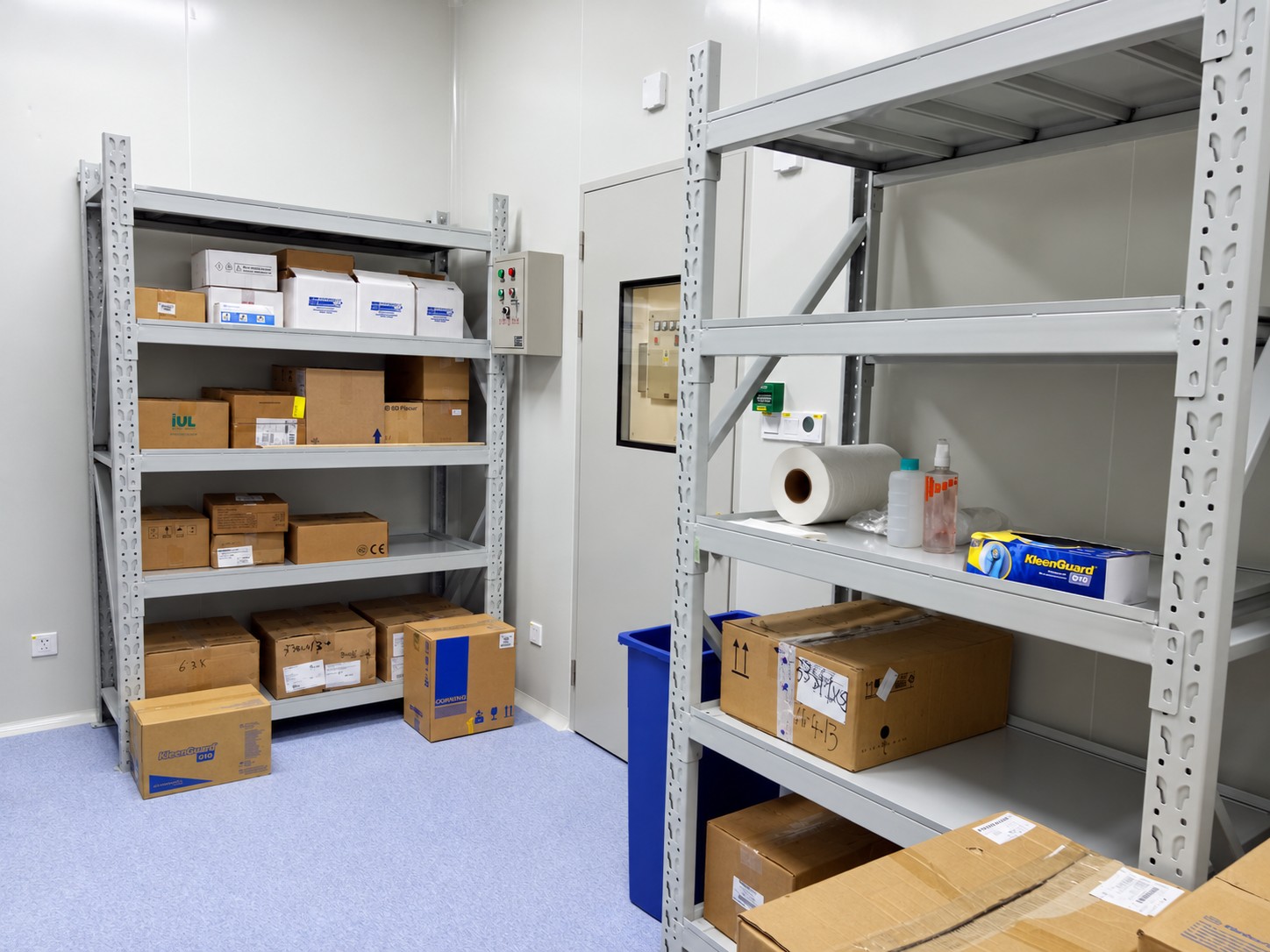 Laboratory supplies storage with metal shelving, packages and a glazed access door