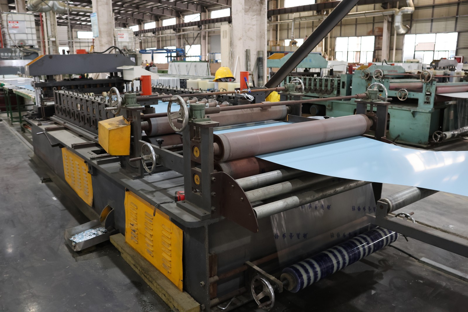 Light blue sheet material passing through processing rollers