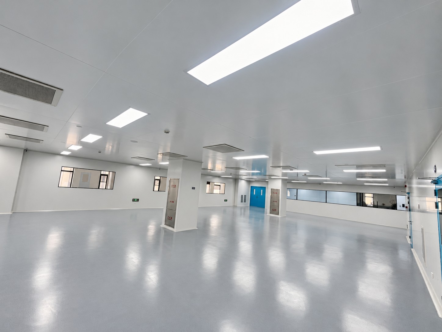 Panel-lined medical-device project room with observation windows and ceiling lighting