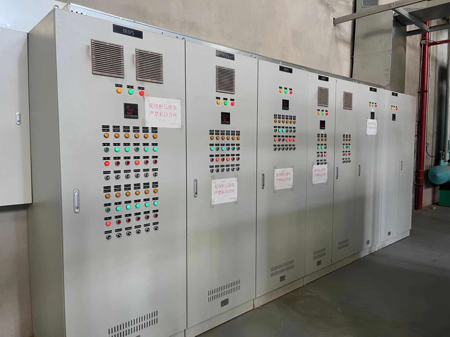 A row of electrical cabinets with vents, indicator lights and control switches