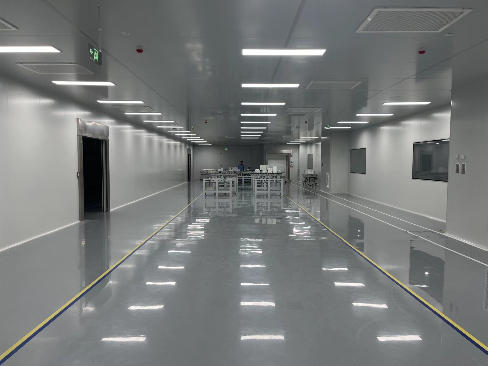 Panel-lined room with ceiling lights, wall windows and equipment at the far end