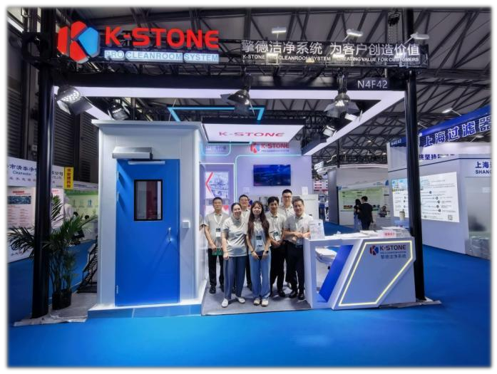 Group posing in front of a K-STONE-branded exhibition booth