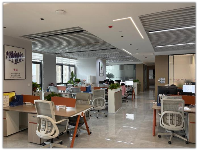Open-plan office with desks, monitors and people working toward the back