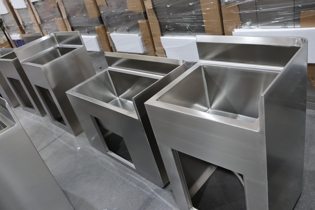 Metal sink assemblies with raised backs and open frames
